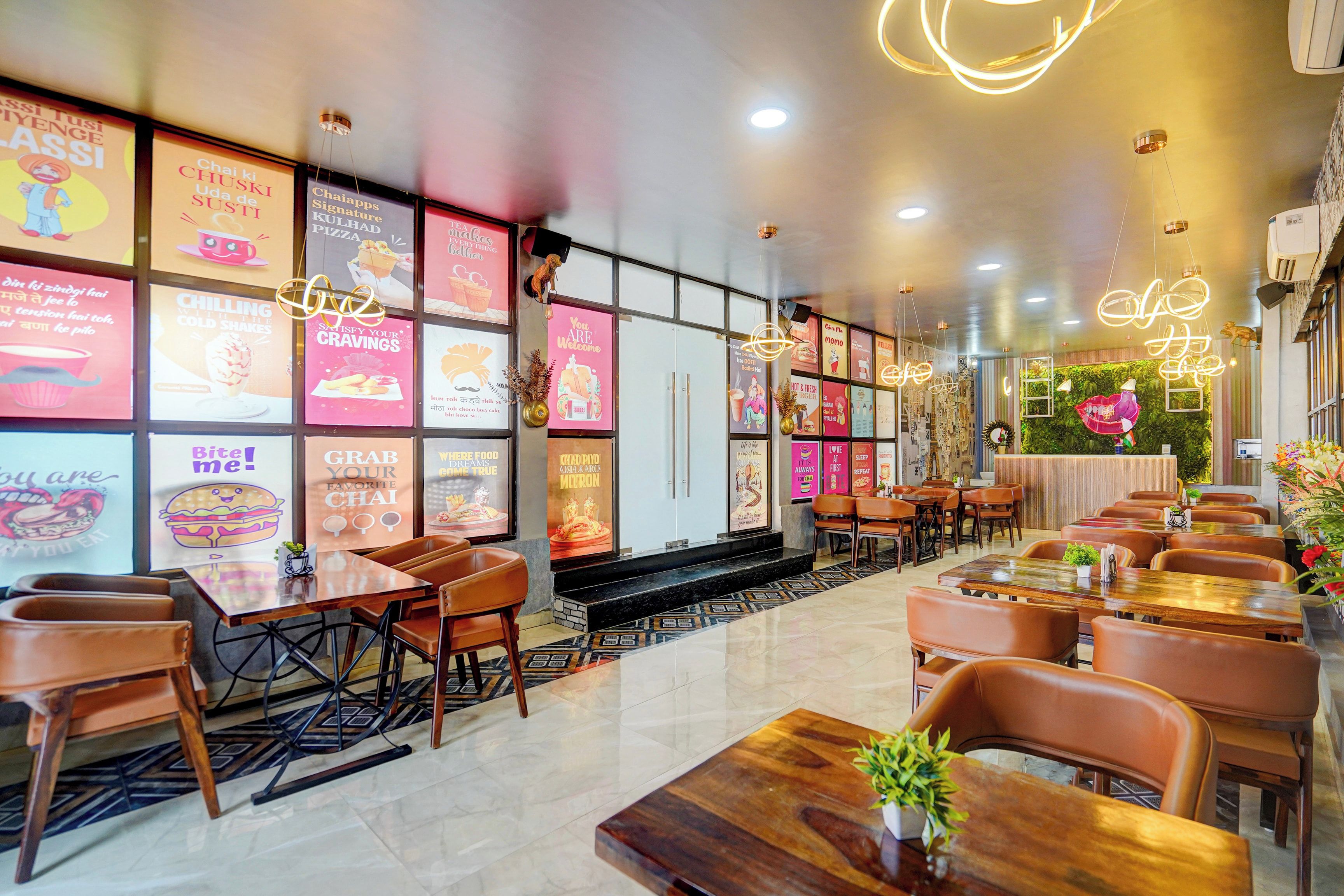 Interior de restaurante con varias mesas y sillas, una variedad de carteles de menú coloridos en las paredes y un diseño de techo moderno.