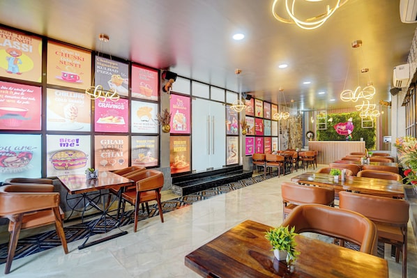 A restaurant interior with multiple dining tables and chairs, a variety of colorful menu posters on the walls, and a modern ceiling design.