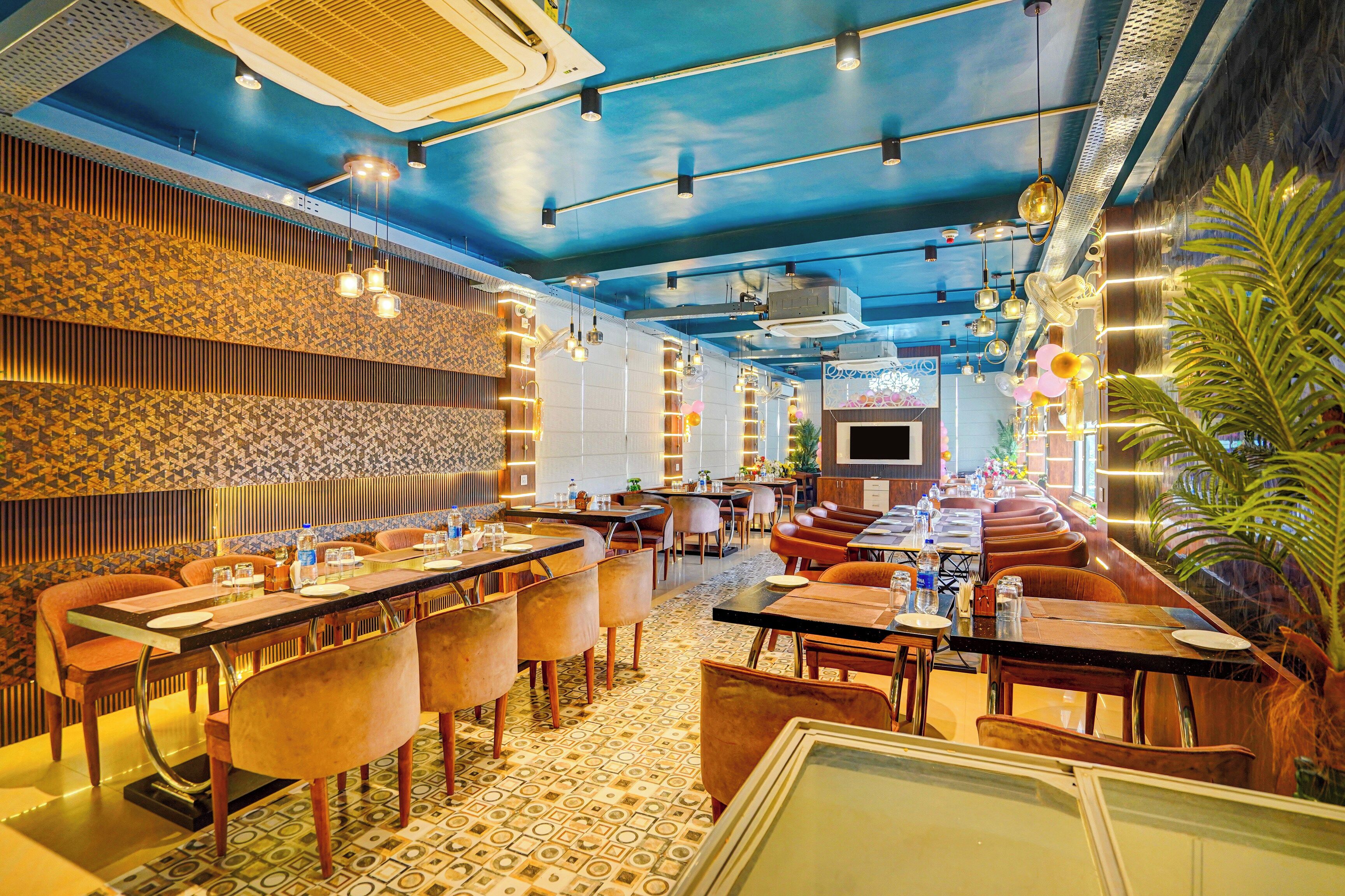 A restaurant with a blue ceiling, patterned walls, and a variety of seating arrangements including booths and tables.