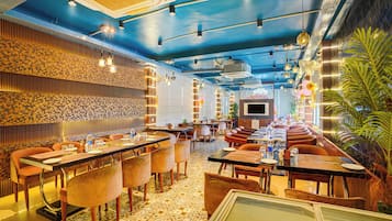 A restaurant with a blue ceiling, patterned walls, and a variety of seating arrangements including booths and tables.