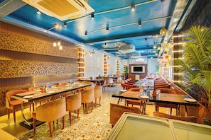 A restaurant with a blue ceiling, patterned walls, and a variety of seating arrangements including booths and tables.