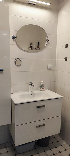 Un bany amb un rentapins blanc, un mirall i un vàter.