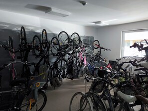 Una habitació amb diverses bicicletes aparcades a la paret, una finestra amb llum natural i un sostre amb ventilació.