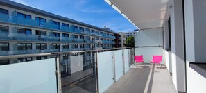 A modern building with a glass balcony, a clear sky, and a bird on the roof. - Elegant Vacation Rental “Apartamenty-plaza” – 300 m from the beach, Kolberg (Kołobrzeg)