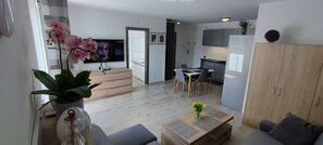 Un soggiorno moderno con un divano, un tavolino da caffè e una televisione sullo sfondo.