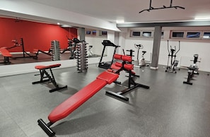 Una palestra con diverse attrezzature per esercizi, tra cui panche e macchinari per pesi.