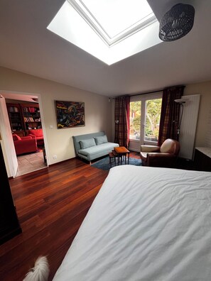 Un dormitorio con tragaluz, un sofá, una silla, una cama y vistas al exterior.