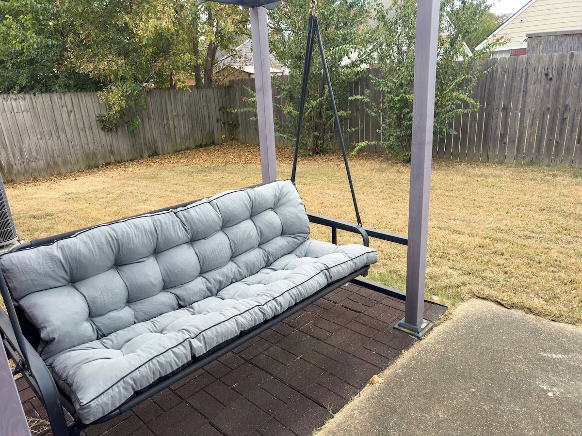 A gray outdoor sofa on a wooden deck with a swing.