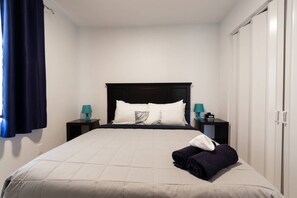 Ein Hotelzimmer mit Bett, zwei Nachttischen, einem Kleiderschrank und einem Vorhang.
