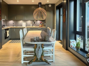 Une cuisine moderne avec des meubles de couleur sombre, un îlot central et un luminaire suspendu.