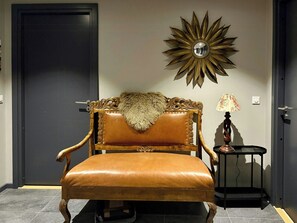 A room with a brown leather chair, a decorative wall mirror, and a small table with a lamp. - Modern apartment with sauna by Sjusjøvannet (Sjusjøen)