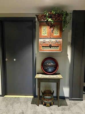 A wooden cabinet with intricate carvings, a framed picture on a small table, and a decorative bowl on the floor. - Modern apartment with sauna by Sjusjøvannet (Sjusjøen)