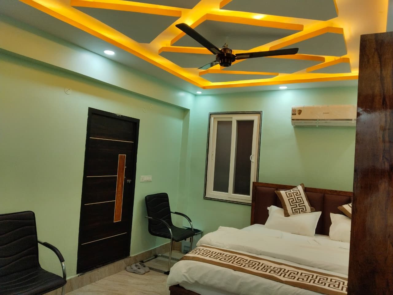 A bedroom with a bed, a chair, a wardrobe, a window, and a ceiling fan.
