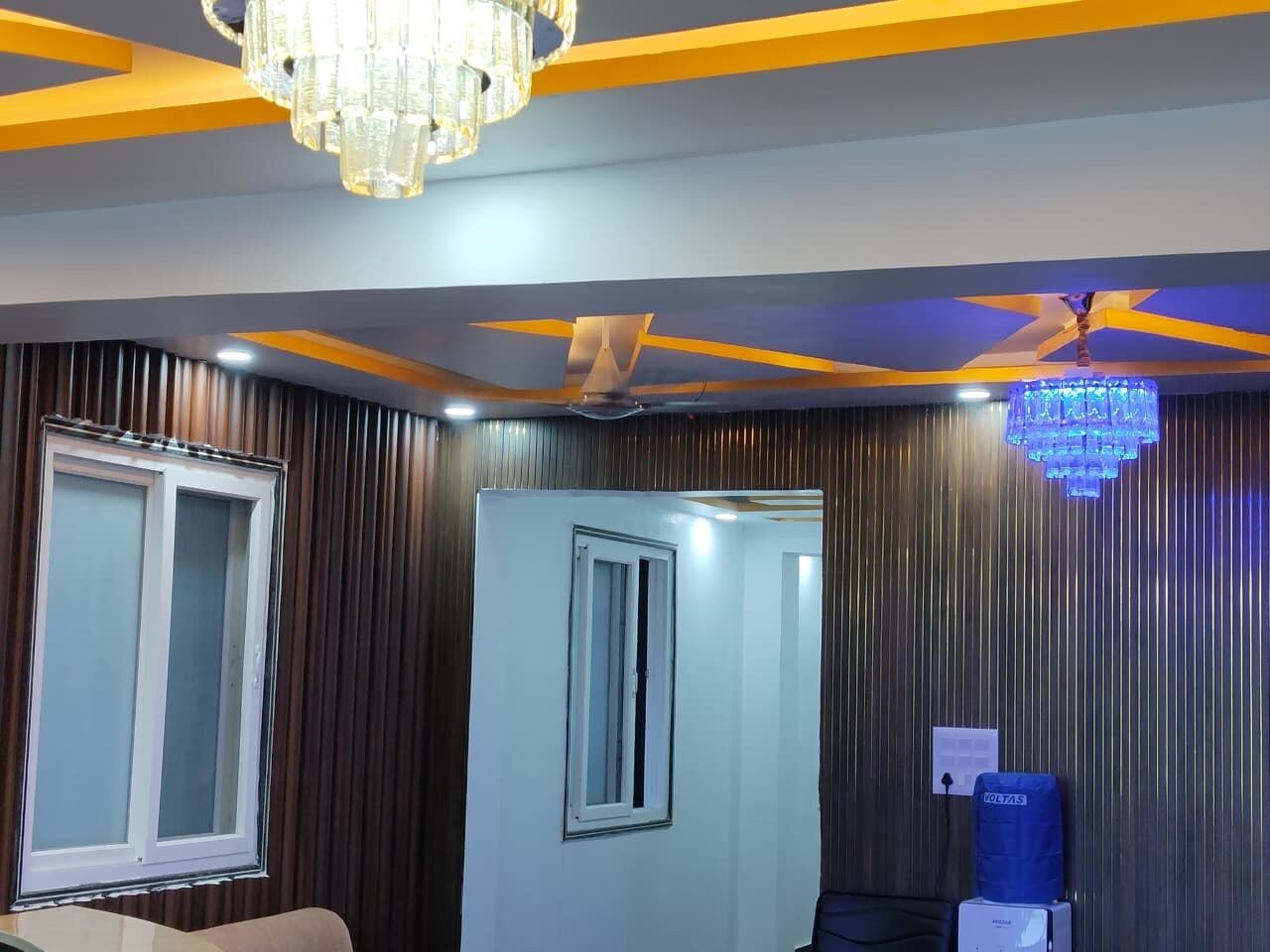 Una habitación con candelabro, ventilador de techo y dispensador de agua.