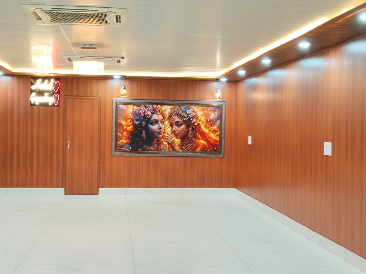 Un hall de hotel con una obra de arte grande enmarcada en la pared, un letrero de neón y una puerta cerrada.