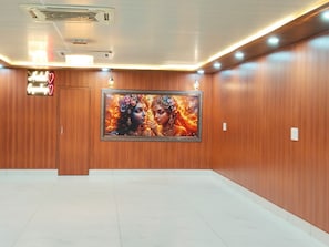A hotel lobby with a large framed artwork on the wall, a neon sign, and a closed door.