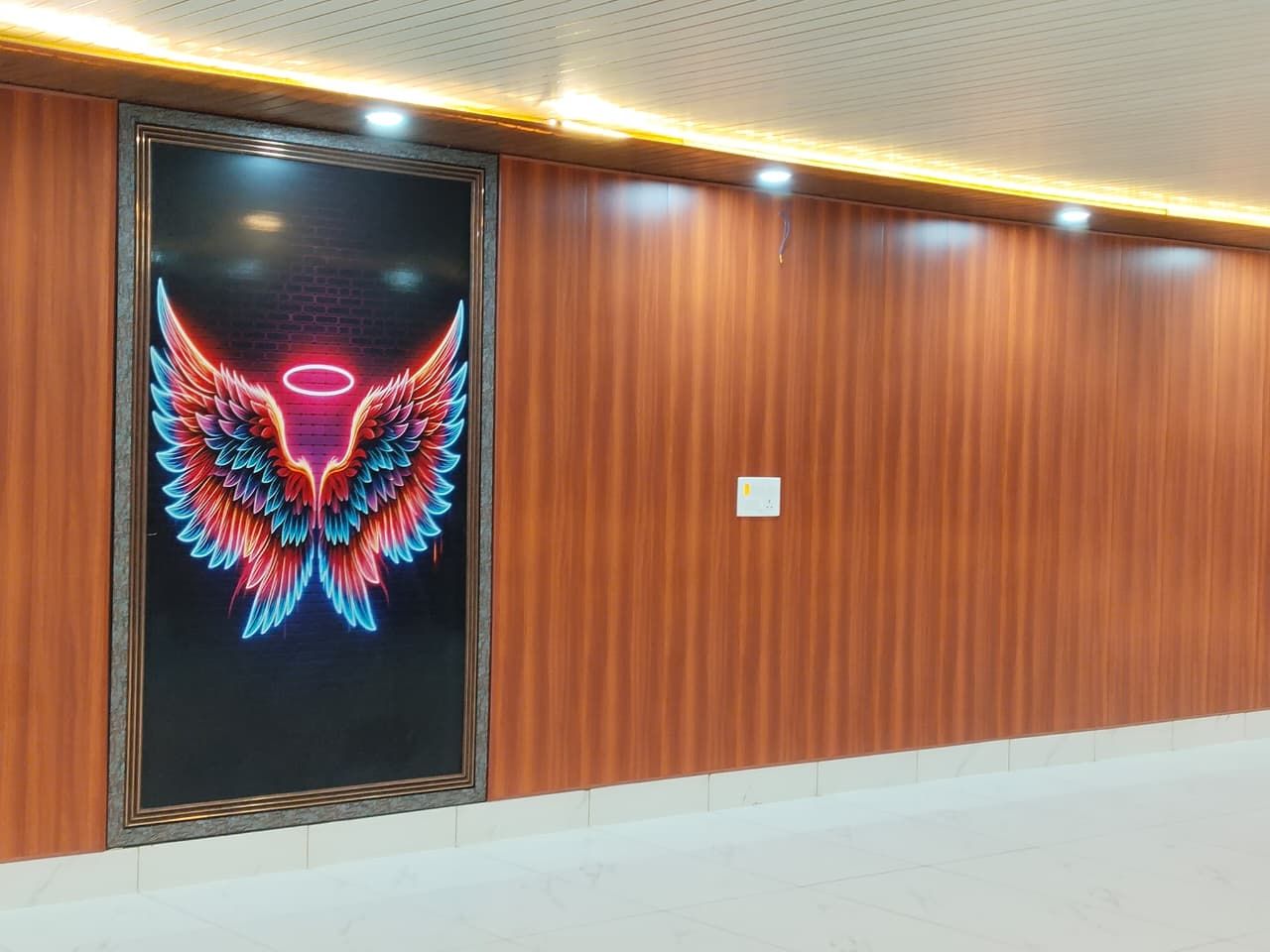 Un pasillo con paneles de madera y un mural de un ángel iluminado con neón en la pared.