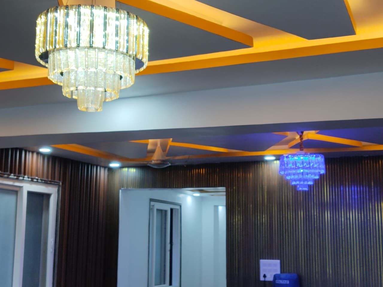 Una habitación con candelabro, ventilador de techo y una puerta.