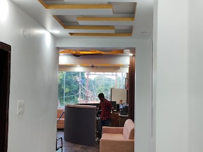Une pièce comprenant un bureau, une chaise, une fenêtre donnant sur des arbres et un plafond avec des poutres en bois.