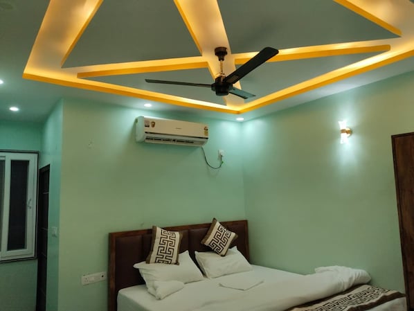Un dormitorio con cama, ventilador de techo y unidad de aire acondicionado.