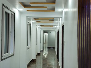 A corridor with white walls, a polished floor, and recessed lighting.