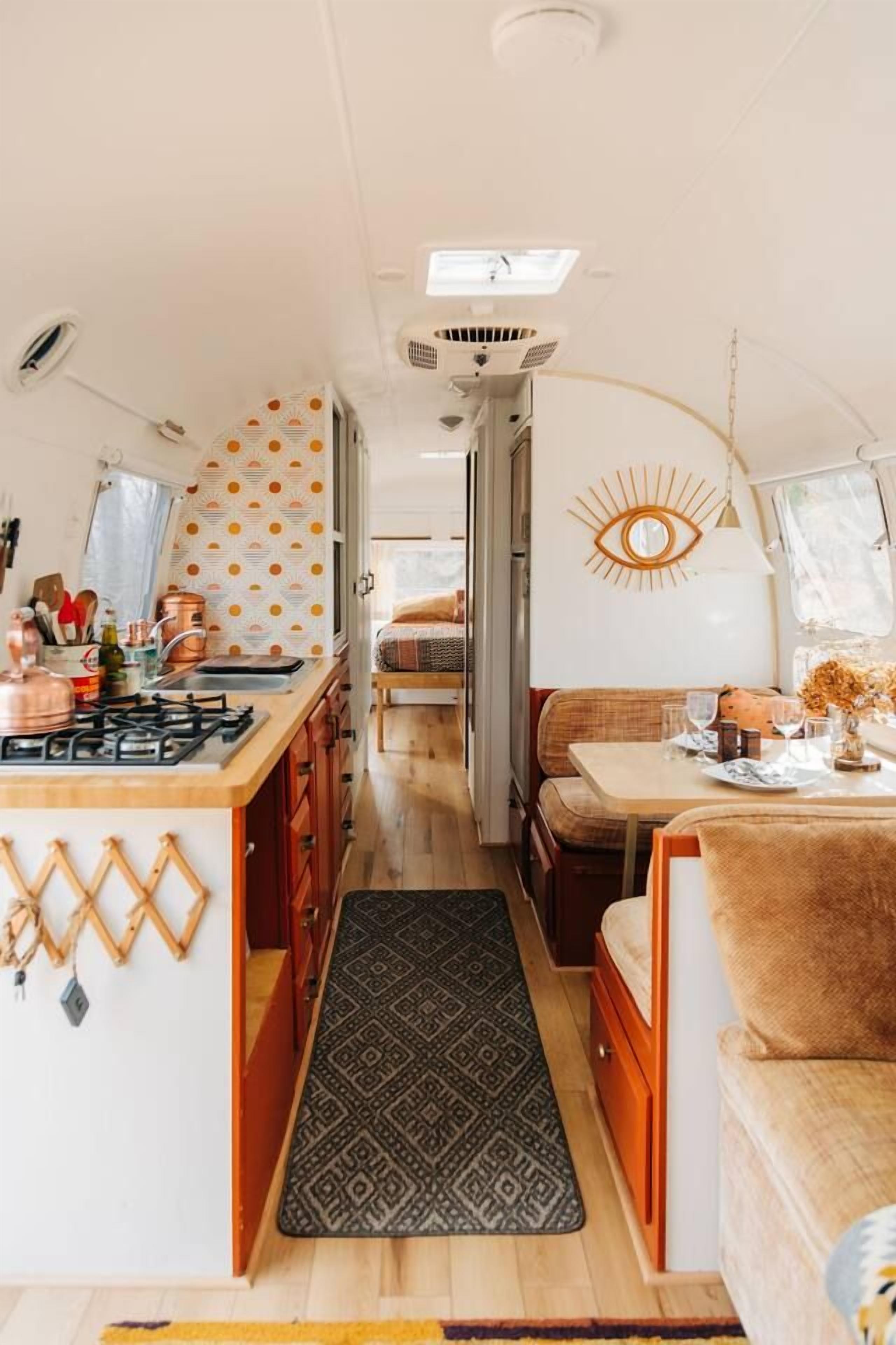 Un intérieur de camping-car compact comprenant un coin cuisine, un espace repas et un espace nuit.