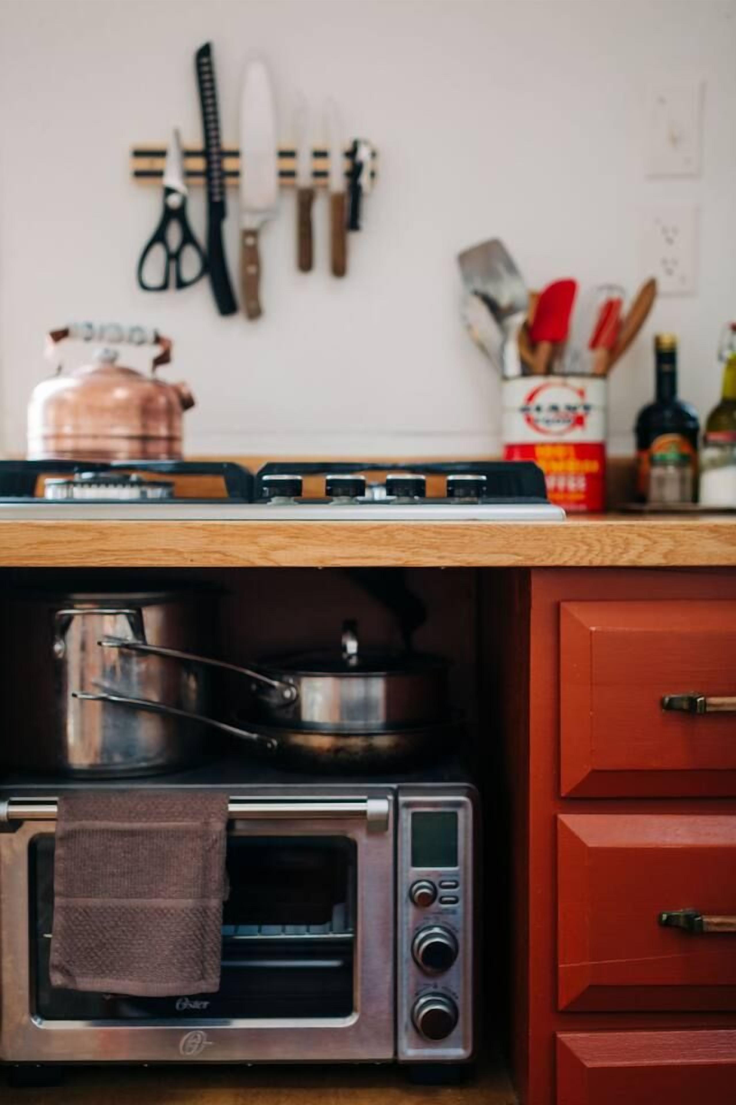 Una cucina con un forno tostatutto, una pentola di rame e diversi utensili da cucina sul piano di lavoro.