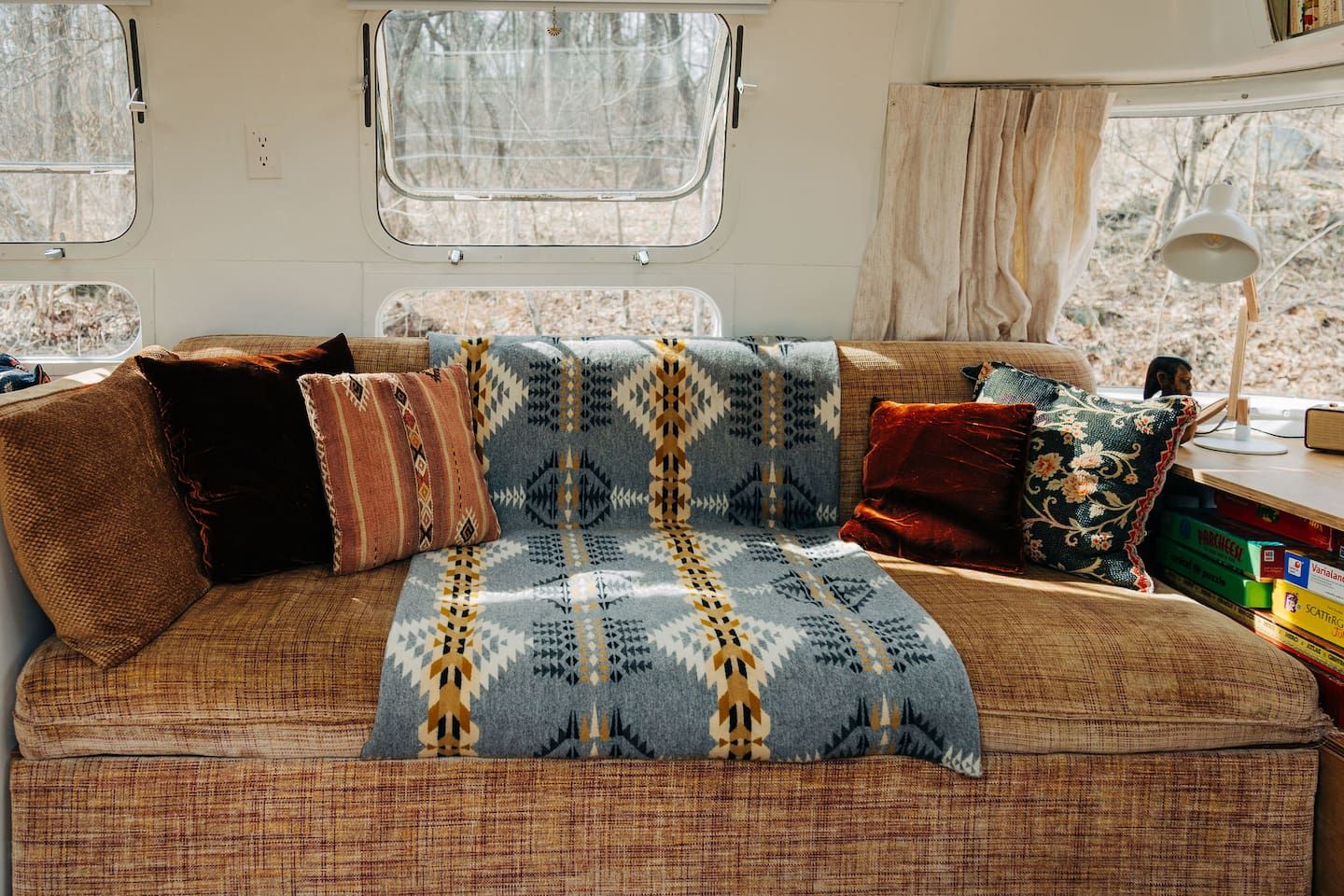 Een gezellig interieur van een camper, met een bank, kussens en een plaid.