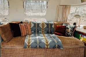 A cozy RV interior with a couch, pillows, and a blanket.