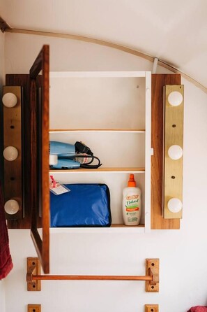 A room with a vanity mirror, a blue bag, and a bottle of hand sanitizer.