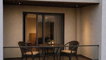 A balcony with a table and two chairs, a potted plant, and a candle.