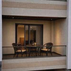 A balcony with a table and two chairs, a potted plant, and a candle.