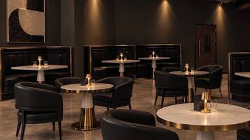 Interior moderno de restaurante con mesas redondas, asientos de cuero negro y un diseño de techo perforado único.