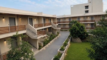 Un edificio moderno con varios balcones, un patio central con jardineras y un cielo despejado.
