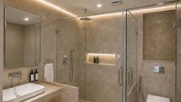 Un baño moderno con ducha de vidrio, tocador doble y un inodoro.