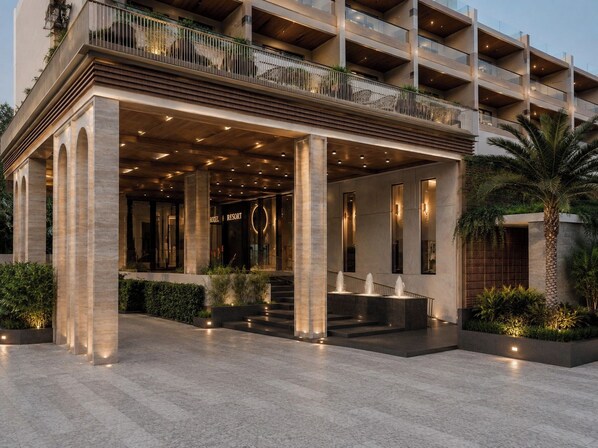 A hotel entrance with a covered outdoor area, columns, and a palm tree.
