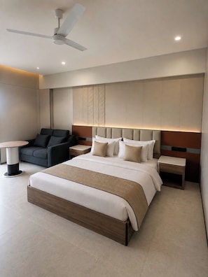 Habitación de hotel moderna con una cama grande, un escritorio, una silla y un ventilador de techo.