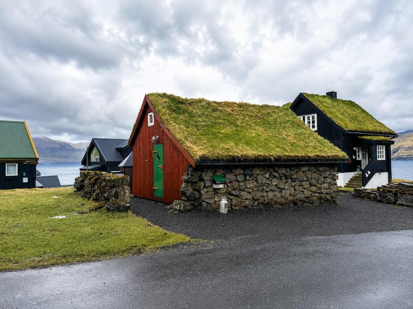 A traditional Icelandic house with a grass roof, stone walls, and a red door.