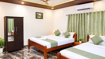 Quarto de hotel com duas camas, um guarda-roupa, ventoinha no teto e ar condicionado, além de uma cortina verde.