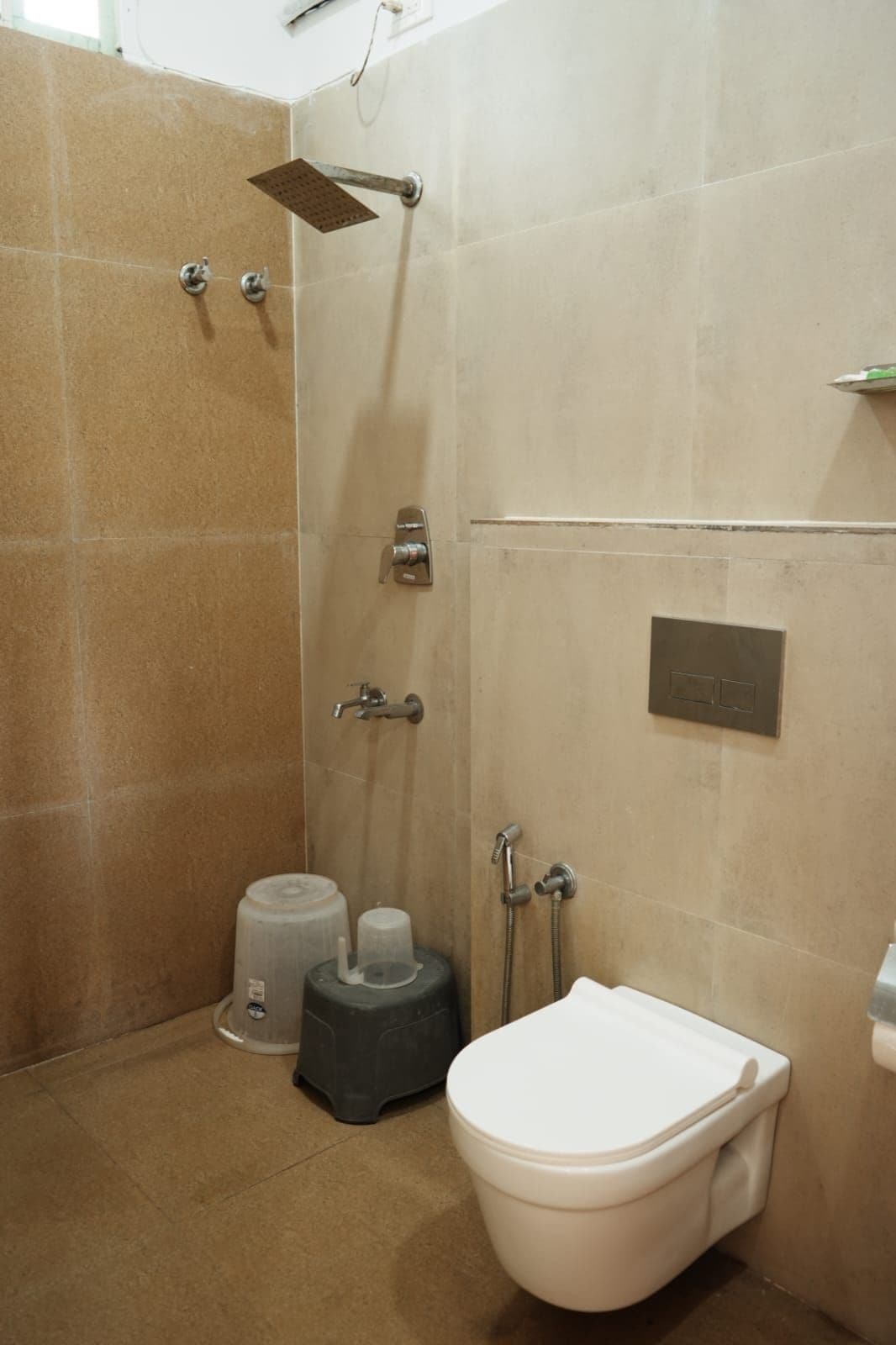 A bathroom with a shower, toilet, and a trash bin.