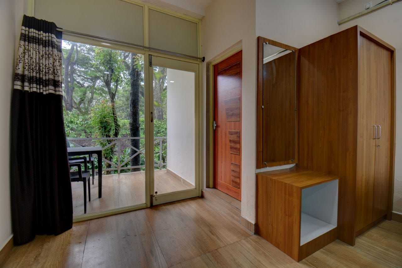Una habitación con puerta corrediza de vidrio que da a un balcón, un armario de madera y una mesa con sillas afuera.