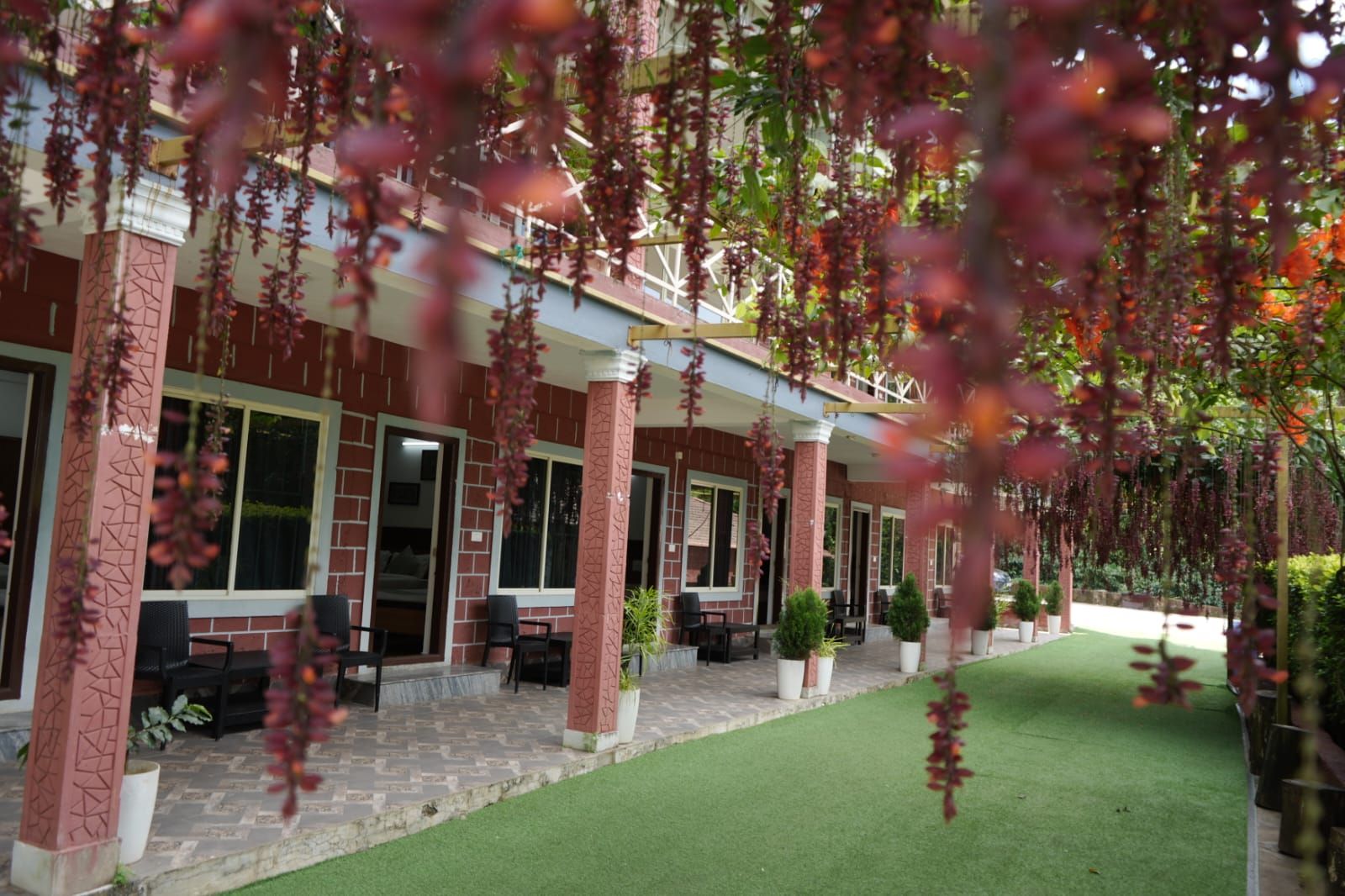 A covered outdoor seating area with brick columns, potted plants, and a well-maintained lawn.
