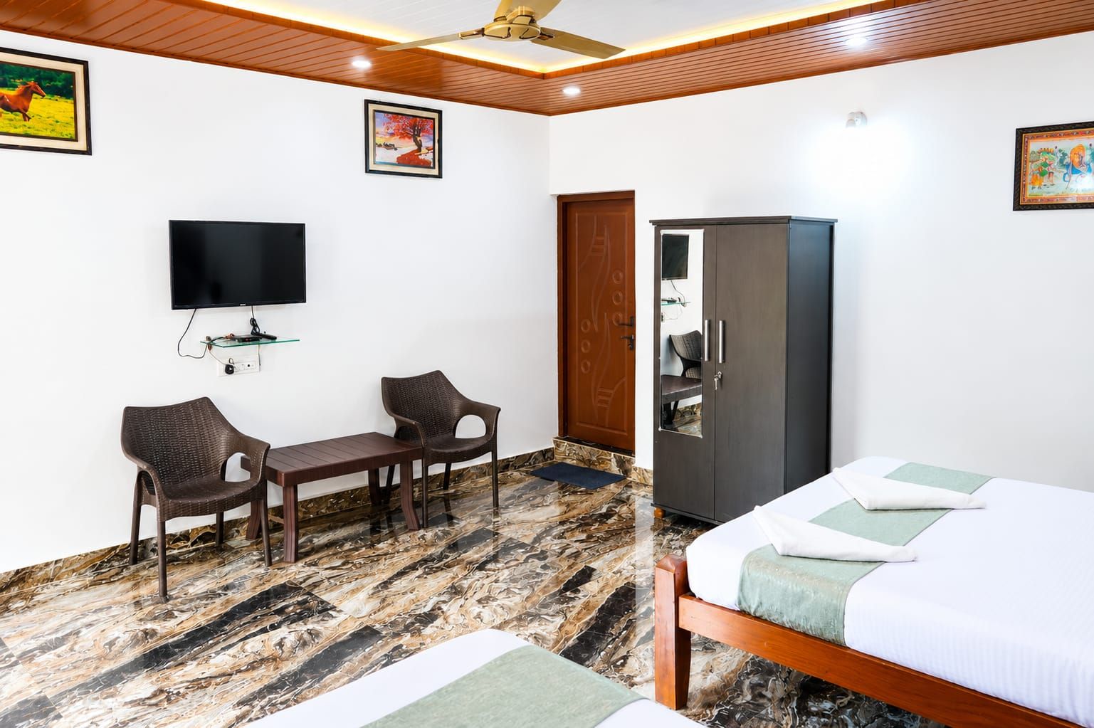 A hotel room with a bed, a desk, two chairs, a TV, and a wardrobe.