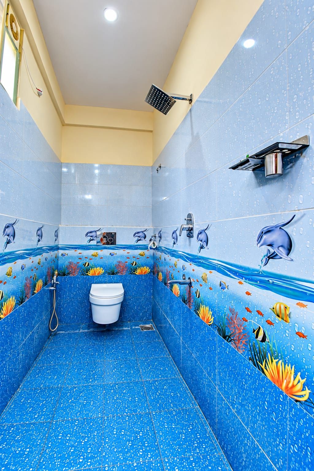 Un baño con piso y paredes de azulejos azules, un inodoro blanco, una ducha y un lavamanos instalado en la pared.
