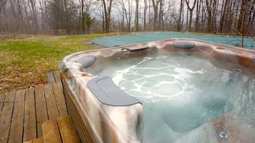 Een hottub met een houten terras en een gazon op de achtergrond.