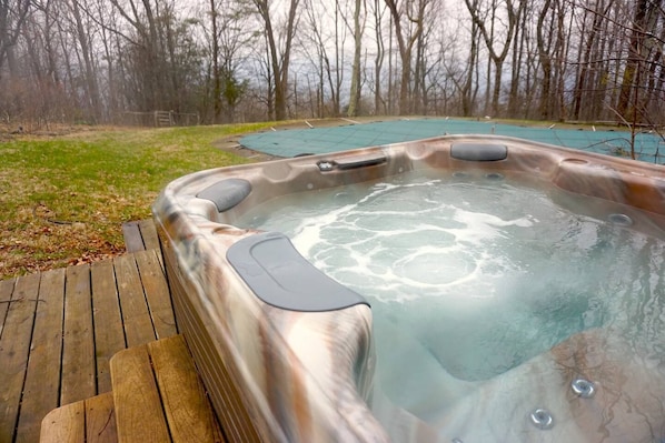 A hot tub with a wooden deck and a grassy area in the background.