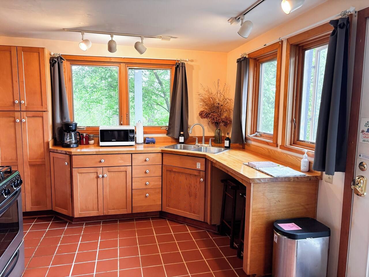 A compact kitchen with wooden cabinets, a microwave, a coffee maker, and a sink.