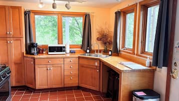 A compact kitchen with wooden cabinets, a microwave, a coffee maker, and a sink.