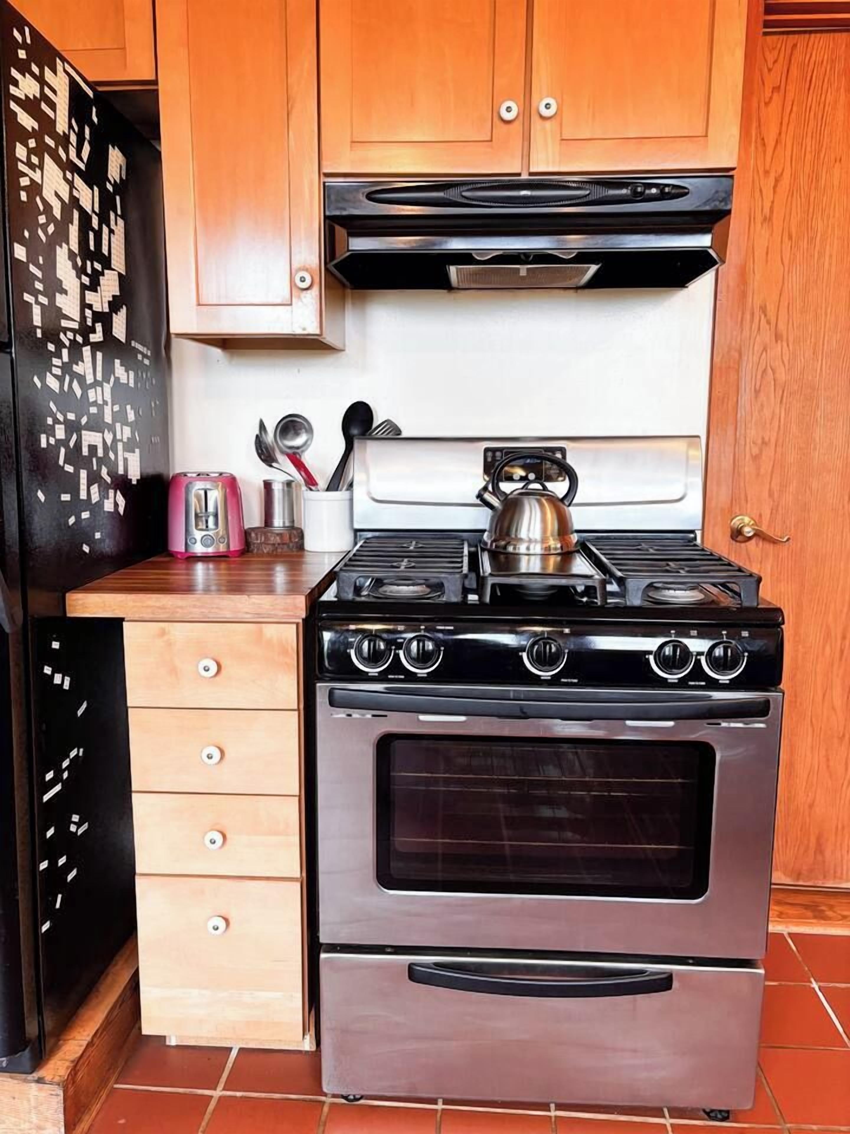 Een keuken met een roestvrijstalen fornuis, oven en een houten aanrecht.