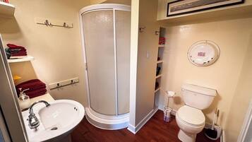 Une salle de bain équipée d’une douche, de toilettes, d’un lavabo et d’étagères.